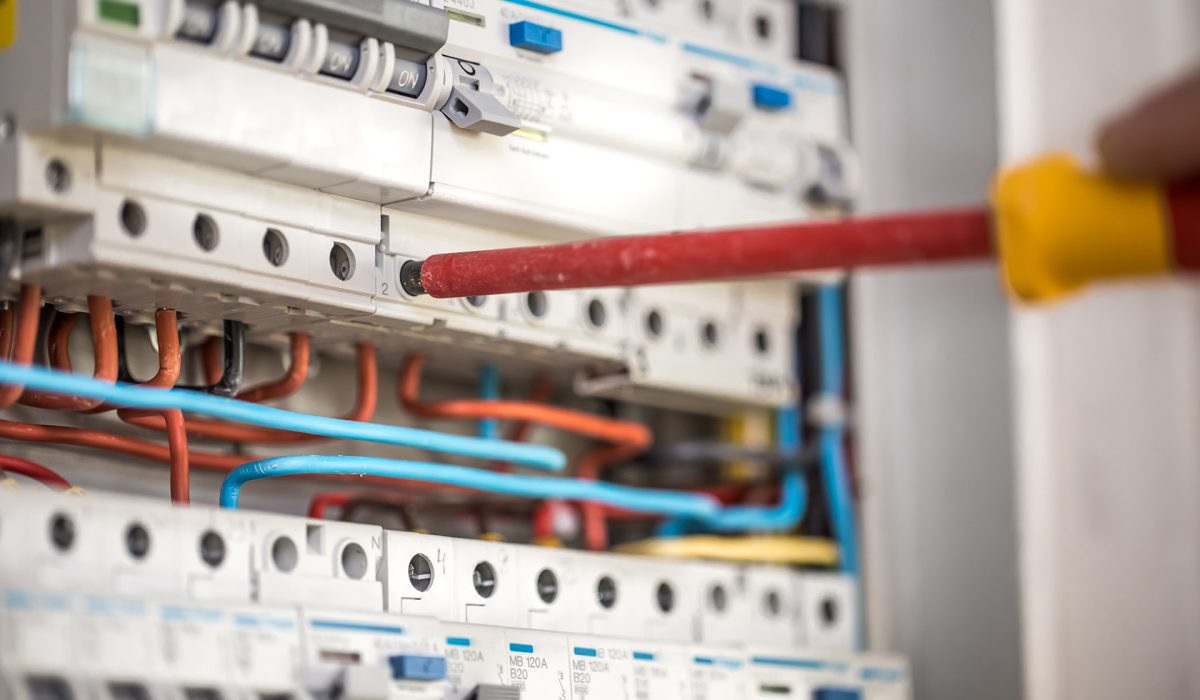 man-electrical-technician-working-switchboard-with-fuses-installation-connection-electrical-equipment-close-up